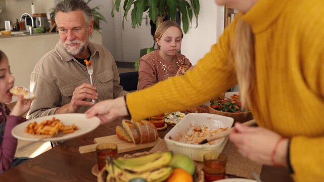 Grandparents, parents, and grandchildren gather around a dining table, sharing a delicious meal and creating lasting memories in a warm and inviting home setting