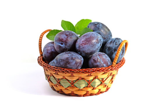 Reife Pflaumen im Korb vor wei&szlig;em Hintergrund