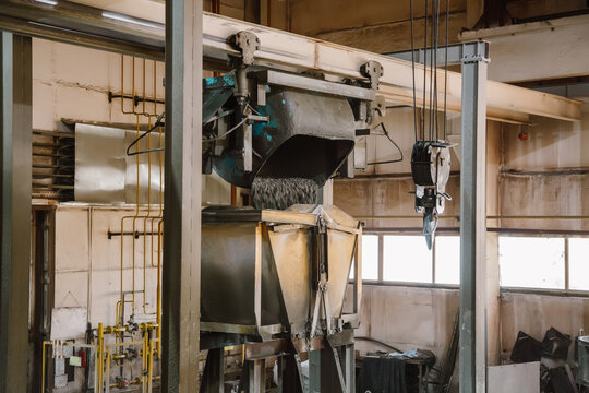 Industrial mixer pouring fresh wet concrete into a hopper at a precast factory workshop