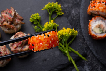 sushi roll in chopsticks and  shiitake mushrooms  beautiful served  at black dish. top view. macro shot