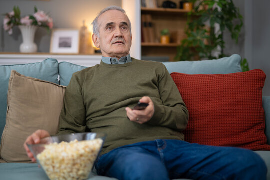 Senior man watching tv enjoying popcorn