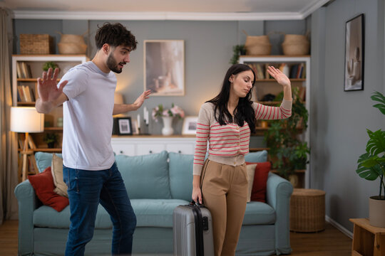 Couple having conflict, woman leaving with suitcase