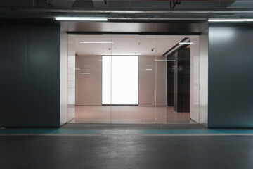 Underground parking garage entrance with glass doors leading to an empty modern office space © zhu difeng