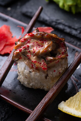 sushi roll in chopsticks beautiful served  at black dish. macro shot