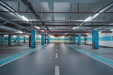 Underground parking garage with empty lanes and blue marked columns under industrial lighting