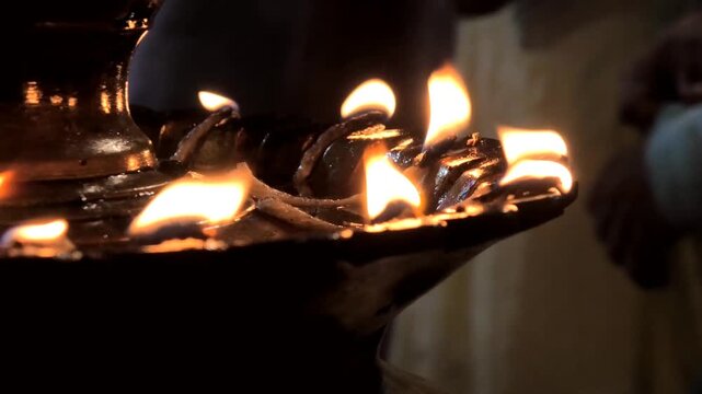 A traditional brass oil lamp lit at the entrance of a temple in Kerala, India