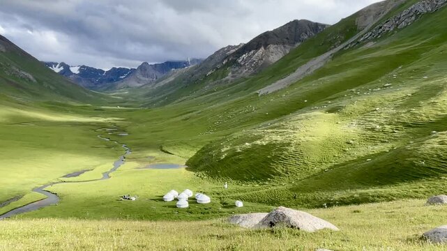 Traditional yurt camp set in the spectacular Terim Tor Valley, Kyrgyzstan, colorful wildflower meadow in the foreground.