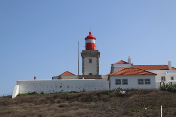 Red lighthouse tower and traditional white buildings at Cabo da Roca, Portugal.