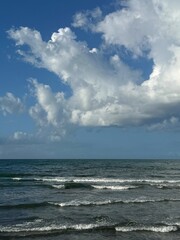 Big fluffy clouds above sea waves.