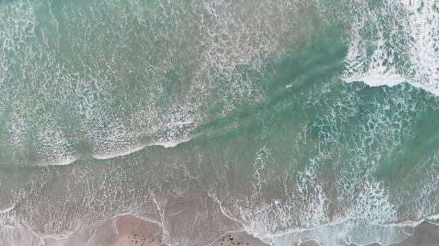 Aerial looking straight down onto large swell and waves. Overhead view of waves splashing along the coastline