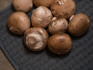 Obraz premium Brown champignon mushrooms on dark fabric background