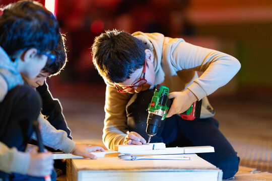 Children learning carpentry skills using power tools