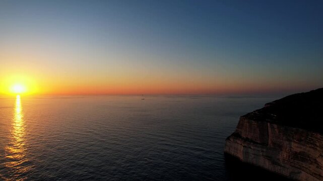 Aerial drone view of the Highest point of Malta at Dingli Cliffs, beautiful lush green grass and rock formations with a steep drop to the sea at sunset, golden hour. Sun giving the golden glow