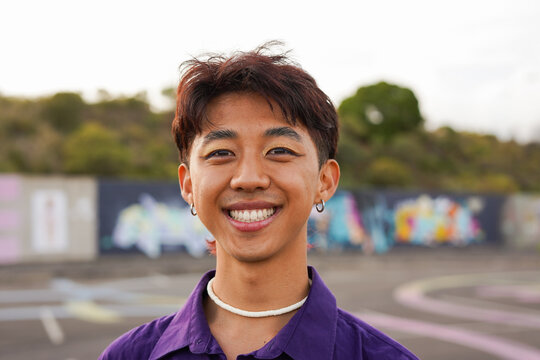 Happy young asian man with make up smiling in front of camera outdoor - LGBT, gay person and generation z concept