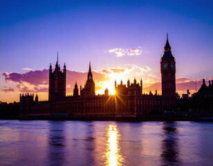 Fototapeta premium Majestic silhouette of iconic clock tower and parliament buildings at dusk. Vibrant sunburst over the Thames river creates a powerful metaphor for history, politics, and scenic travel.