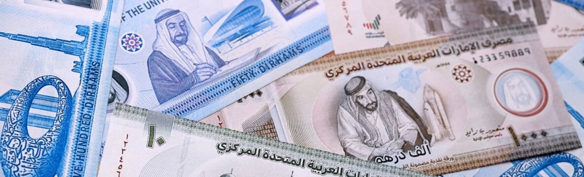 UAE dirham money bills pile on table. United Arab Emirates banknotes of AED currency close up.