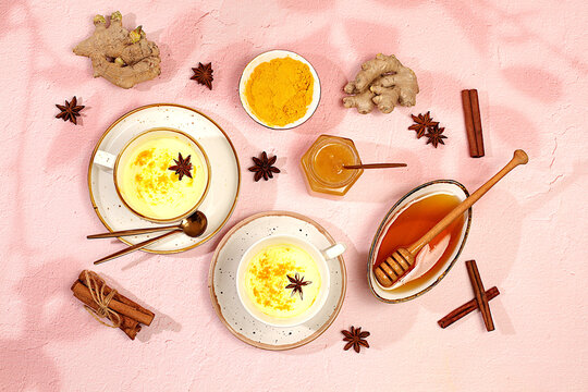 Golden turmeric latte with ginger, cinnamon, anise and honey spices on sunny table. Weight loss and alternative medicine concept, immunity booster during pandemic, Indian cuisine advertisement.