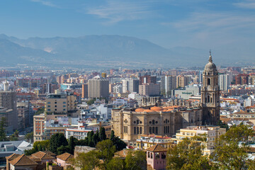 Obraz premium Malaga Cathedral and city skyline with modern architecture and mountain landscape viewed from Gibralfaro hill viewpoint in La Malagueta district under a clear blue sky in Andalusia Spain.
