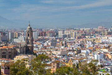 Obraz premium Malaga city skyline with historical architecture and modern residential buildings in La Malagueta district viewed from a high viewpoint under a clear blue sky in Andalusia Spain coastal area.