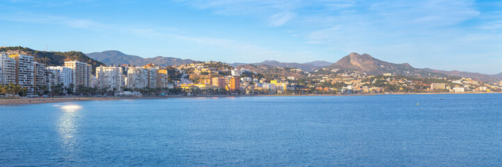 Obraz premium Malaga Spain panoramic view of the coastal city skyline with residential buildings along the mediterranean sea and mountains in the background during a bright evening in andalusia