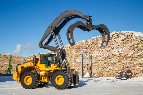 Loading logs with a special loader.Timber products warehouse on a specialized site.