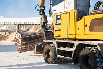 Obraz premium Loading logs with a special loader.Timber products warehouse on a specialized site.