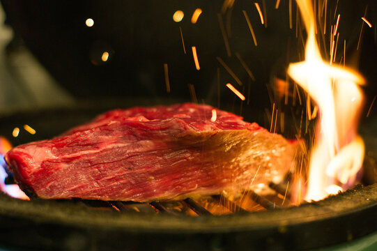 A large steak on the big green egg barbecue grill with flames