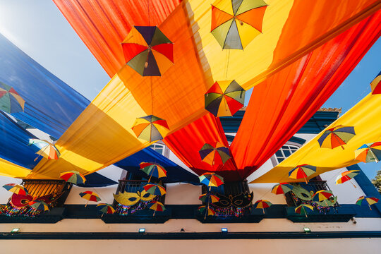 Decora&ccedil;&atilde;o de rua com sombrinhas de frevo e tecidos coloridos durante o Carnaval de Tiradentes, cidade hist&oacute;rica de Minas Gerais, Brasil.