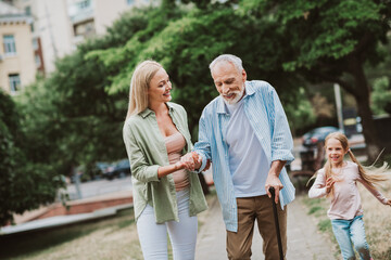 funny creative title about a happy family walk through the park with grandpa in a wheelchair...