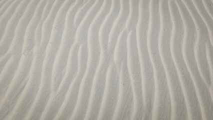 Obraz premium Sand dune patterns created by wind in a desert landscape under bright sunlight