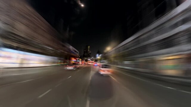 BANGKOK, THAILAND - NOV 2025 : Night city drive through the vibrant and busy streets around Sukhumvit filled with neon lights of the nightlife entertainment district and urban traffic. Time lapse shot
