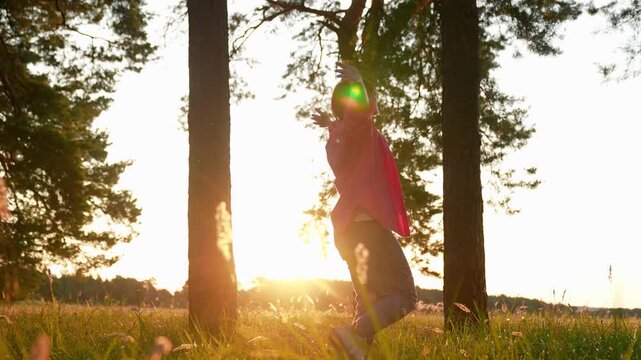 Woman walking in park in summer among trees, raising arms twirling joyfully. Slow motion. Woman's happiness in nature. Happy woman enjoying forest. Girl hiking through forest, relaxing in nature.