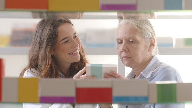Female Pharmacist Recommending Throat Lozenges to Senior Woman