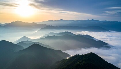 Fototapeta premium Majestic mountains shrouded in misty fog at sunrise from a high aerial viewpoint