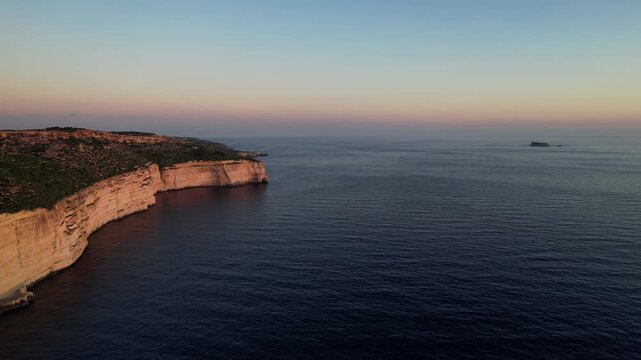 Aerial drone view of the Highest point of Malta at Dingli Cliffs, beautiful lush green grass and rock formations with a steep drop to the sea at sunset, golden hour. Sun giving the golden glow