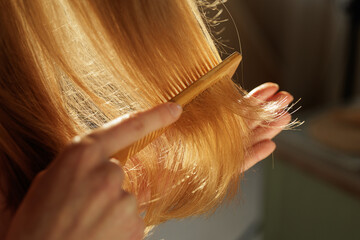 Woman Combing Smooth Long Blonde Hair Showing Healthy Shine Closeup