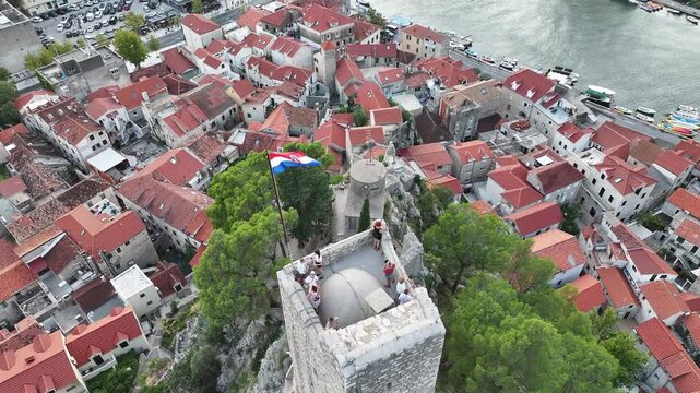 Tourists standing on Mirabela fortress enjoying view of Omis and Adriatic coast.