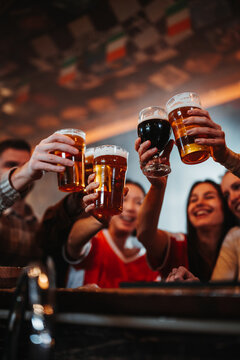 Friends cheering beer glasses enjoying celebration in bar