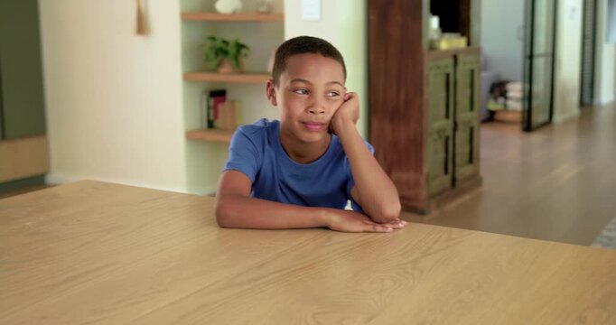 African preteen boy sitting at wooden table, resting, smiling and laughing while camera approaching
