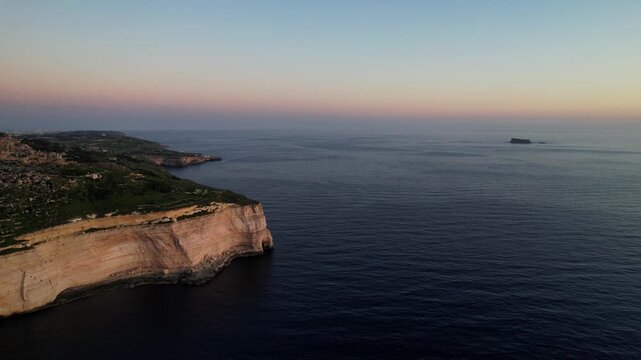 Aerial drone view of the Highest point of Malta at Dingli Cliffs, beautiful lush green grass and rock formations with a steep drop to the sea at sunset, golden hour. Sun giving the golden glow