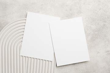 Wedding invitation card mockup with two blank white cards on a textured surface with curved lines, ideal for design and personalization purposes