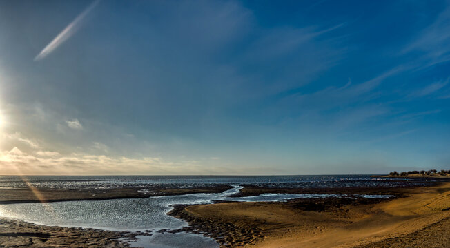 Low tide at Walvis Bay lagoon with sandbars and distant flamingos, Namibia.