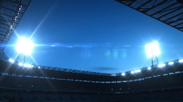Low-angle view of a dimly lit sports stadium with bright floodlights shining against a blue evening sky.