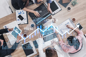 A top-down view of a diverse business team engaged in a meeting, analyzing financial data on...