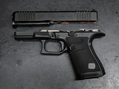 TALLINN, ESTONIA - FEBRUARY 18, 2026: Field stripped Glock 19 Gen 6 9x19mm pistol showing internal components on dark background.