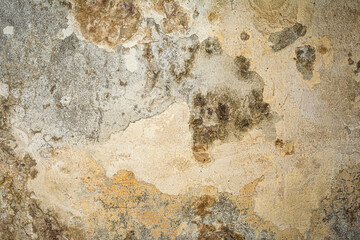 Close-up of a heavily textured and crumbling old plaster or concrete wall surface. The rough, damaged facade shows signs of decay and age, ideal for a grunge background or industrial design element. © Aliaksei