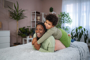 Fototapeta premium African American mother and child playing on bed