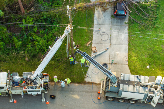 Electrician workers fixing power lines after outage. Repair of damaged electrical wires after hurricane in Florida suburban area