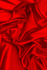 Red silk or satin luxury fabric texture can use as abstract background. Top view.