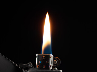 Glowing flame on gasoline lighter on black background